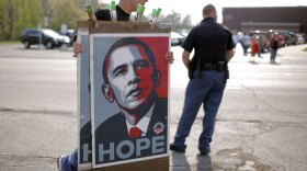 A vendor carries the iconic blue and red Obama posters to a town hall-style meeting the now president held in 2008.