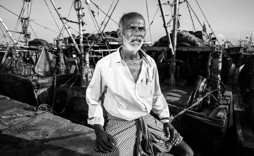 Nandu Kumar, 65, sits among fishing boats at Kasimedu Fishing Harbour in Chennai, India. A former fisherman who now sells fish on shore, Kumar says he once smuggled imported alcohol and cigarettes to make a living.