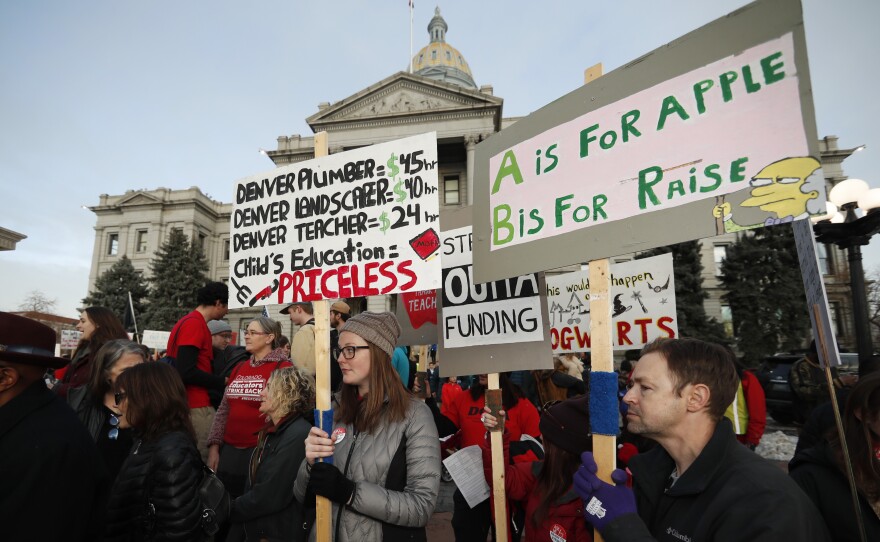 Denver teachers carry placards as they wait to march after a rally in support of a strike outside the state Capitol last month. Denver schoolteachers are going on strike over how their base pay is calculated.