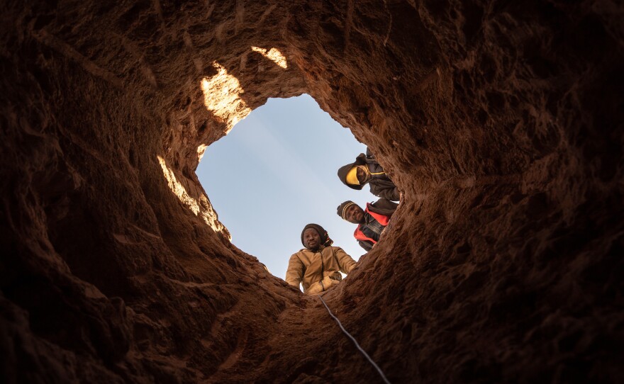 Members of an illegal diamond mining collective look down a mineshaft at the Nuttabooi mine.