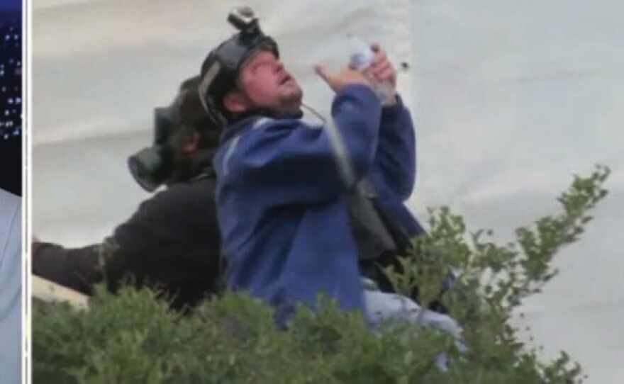 The U.S. government says in its affidavit that this photo shows Guy Reffitt rinsing his eyes outside the Capitol on Jan. 6, 2021, wearing a blue jacket over a tactical vest and a helmet with a camera.