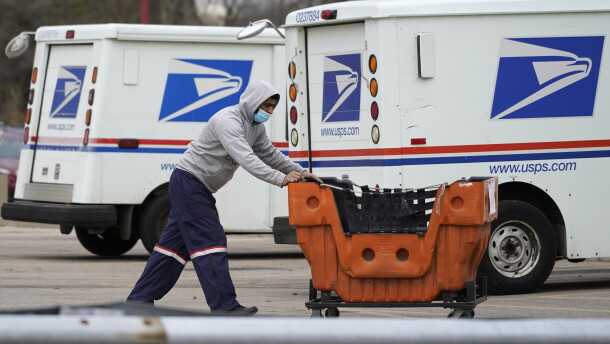 A U.S. Postal Service employee pushes a cart outside a post office in Wheeling, Ill., in 2021.