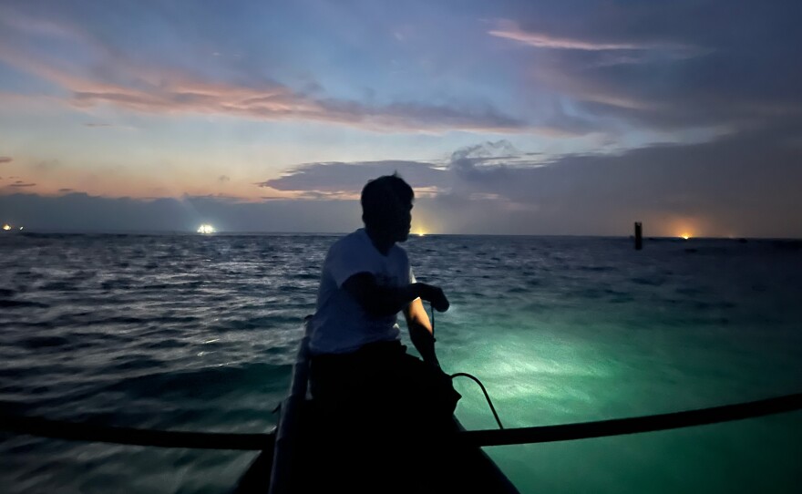 Resident Rolly Dela Cruz, getting ready to go spearfishing off the coast of Thitu Island. On the horizon, several Chinese fishing boats are floating, using bright lights to attract fish.