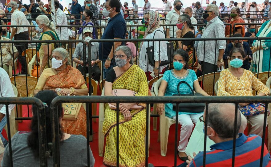 People line up to receive a COVID-19 vaccine on Tuesday in Mumbai.