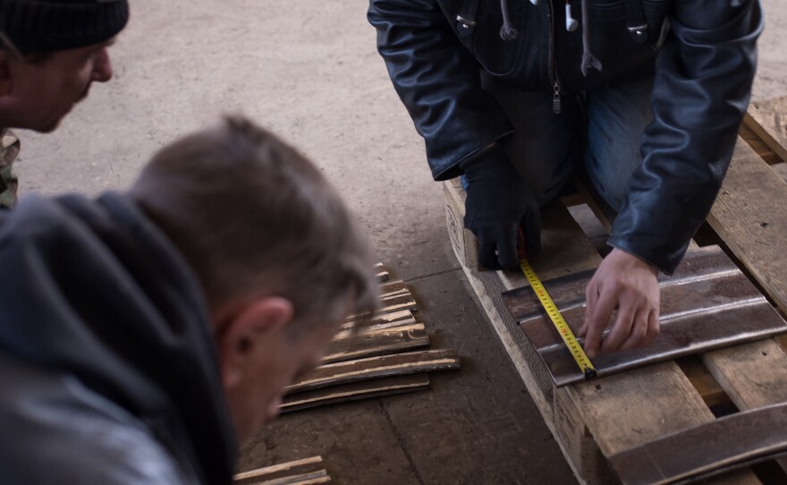 Volunteers measure pieces of scrap steel that will be welded together to make plates.