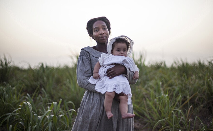 July (TAMARA LAWRANCE) holding a baby.