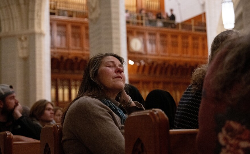 At the OneLewiston Community Vigil, an attendee closes their eyes as the Bates College Crossbones perform <em>Run to You</em> by the Pentatonics in the Basilica of Saints Peter and Paul in Lewiston, Maine.