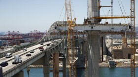In this July 2, 2018, photo, traffic moves on the old Gerald Desmond Bridge next to its replacement bridge under construction in Long Beach, Calif.