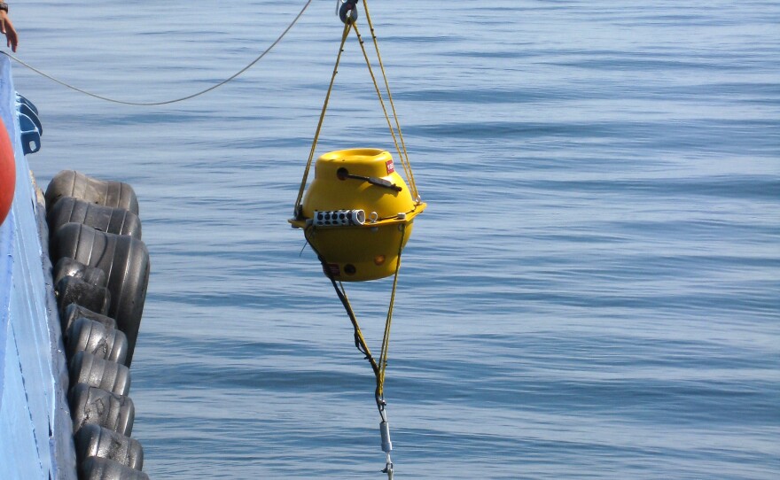 Underwater acoustic recording units being dropped with sandbags into the Massachusetts Bay. These recorders are housed in a pressurized glass sphere and have been successfully deployed around the world from tropical waters to the polar seas.