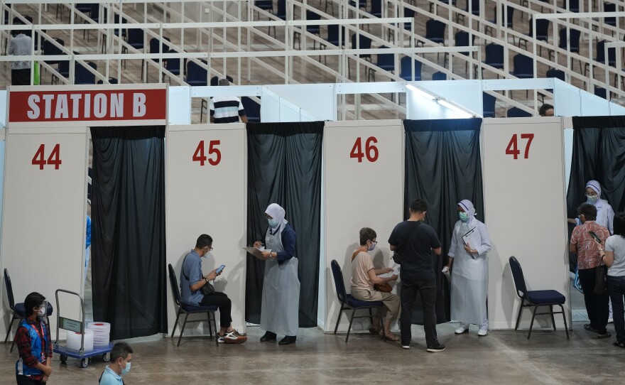 Health staff and patients at an exhibition center in Kuala Lumpur that's been turned into Malaysia's first mega-vaccination center. The government aims to speed up inoculations amid a sharp spike in infections.