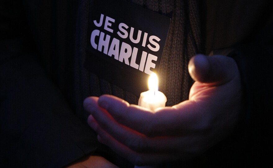 A man holds a candle and a sticker reading " I am Charlie", during a demonstration in Paris, on Wednesday.