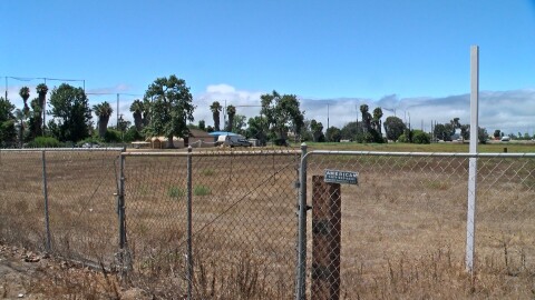 The site for the Bella Mar Apartments project is seen behind a chain link fence, Aug. 15, 2025.