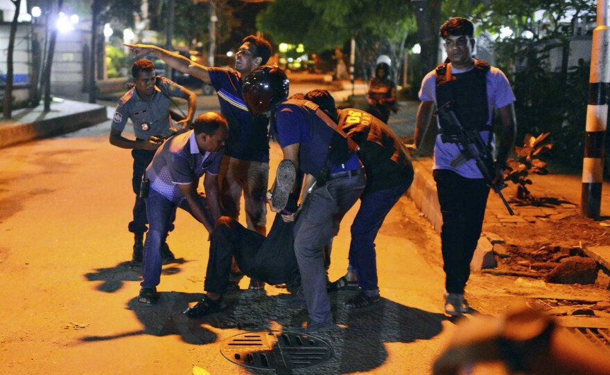 People help an unidentified injured person after gunmen attacked a cafe popular with foreigners in Bangladesh's capital, Dhaka, on Friday.