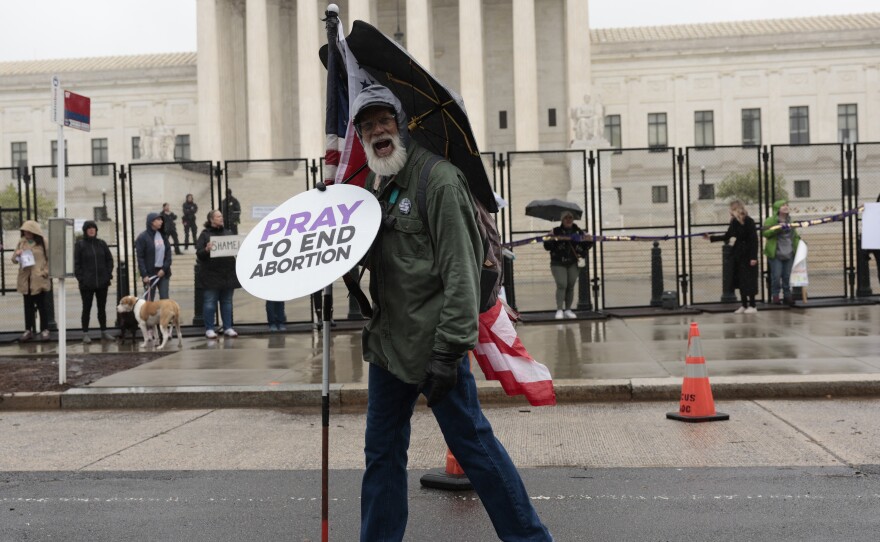 An anti-abortion protester walks past as abortion-rights activists participate in a demonstration in front of the Supreme Court on Saturday.