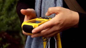 A treasure tracker uses a GPS navigation system in the adventure-filled game of geocaching. 