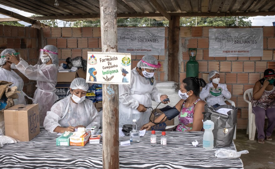 Indigenous healthcare workers wearing PPE treat patients at the Indian campaign hospital set up in the Parque das Tribos neighborhood of Manaus, Brazil, on Tuesday, Jan. 19, 2021. Severe oxygen shortages at hospitals in Brazil's Amazon prompted local authorities to impose a curfew and airlift patients to other states to deal with the onslaught of a second coronavirus wave.