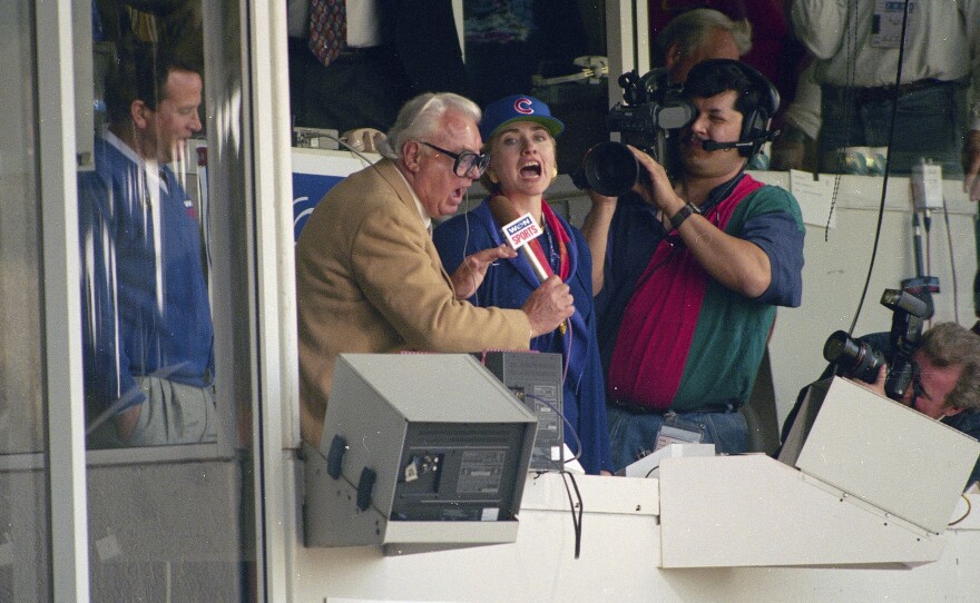 Hillary Clinton, middle, who was First Lady at the time, and Chicago Cubs announcer Harry Caray, left, sing "Take Me Out To The Ball Game" during the seventh inning stretch at Wrigley Field in Chicago in 1994.