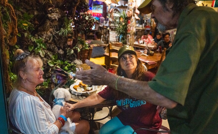Anna Wagenfuehrer, left, whose home in Lahaina burned in the fire, sits with Michelle Belch, who lives nearby, at Java Jazz. They speak with musician Rick Glencross, who also lost his home, about what it was like to flee the flames.