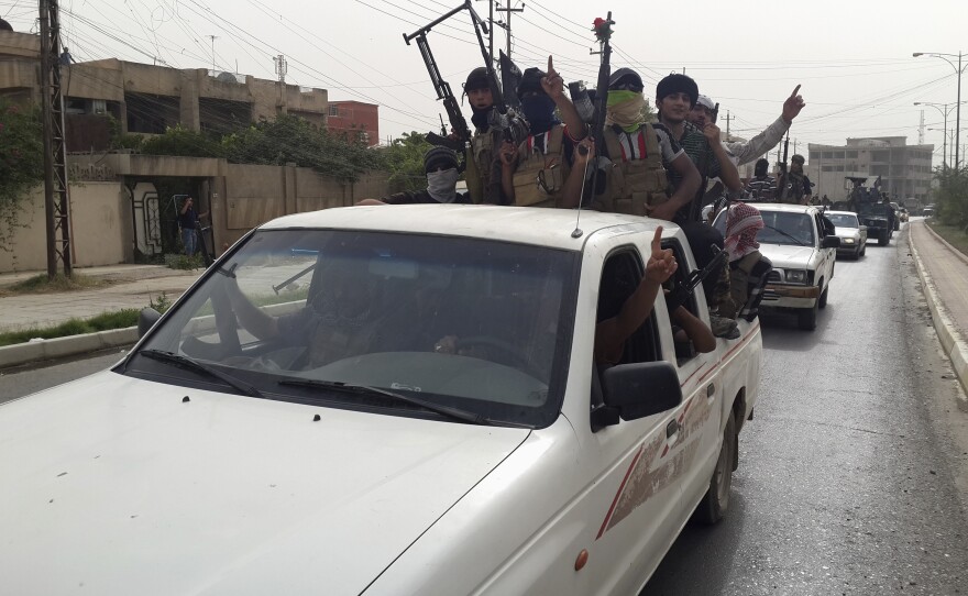 Fighters of the Islamic State of Iraq and Syria celebrate on vehicles taken from Iraqi security forces in Mosul, Iraq, on Thursday.