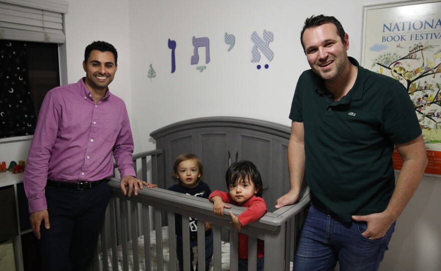 Elad Dvash-Banks (left) and his husband, Andrew, pose for photos with their twin sons, Ethan (center right), and Aiden in their apartment last year in Los Angeles.