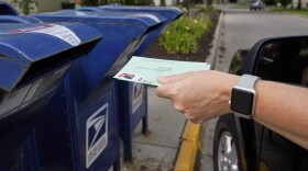 In this Tuesday, Aug. 18, 2020, file photo, a person drops mail into a mailbox. 