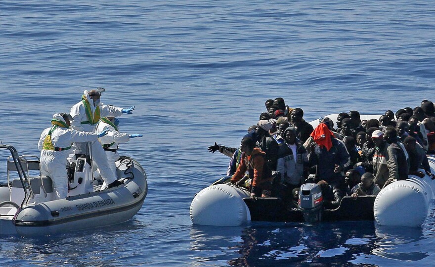 In this photo made available Thursday, April 23, 2015, migrants crowd and inflatable dinghy as the Italian Coast Guard approaches them, off the Libyan coast, on Wednesday.