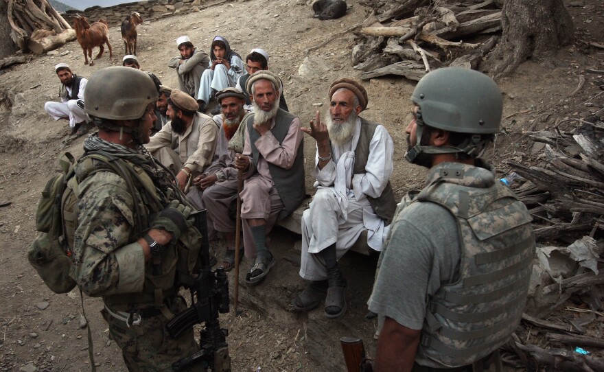 Village elders speak with a U.S. Marine through an interpreter as American and Afghan forces search for weapons in the Korengal Valley of Kunar Province in eastern Afghanistan in 2008.