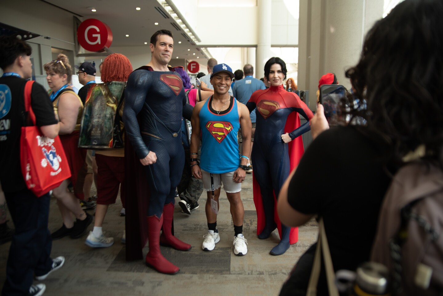Dan Richard (left) and Carmen Estrada (right), cosplaying Superman and Superwoman, take a photo with Clark Pagauan on July 25, 2025.