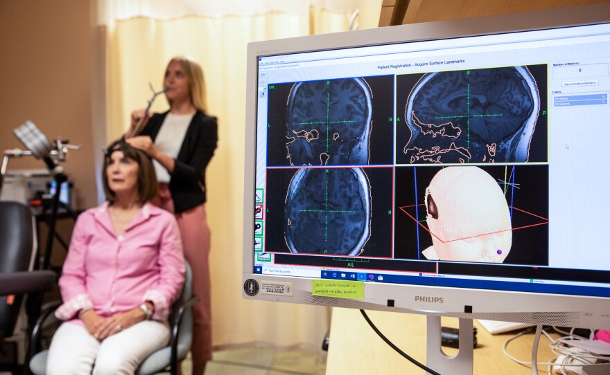 Eleanor Cole, Ph.D., demonstrates the treatment on trial participant Deirdre Lehman in May 2019 at the Stanford Brain Stimulation Lab.
