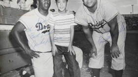 At ANTIQUES ROADSHOW in Palm Springs, California, a guest brings in this 1956 signed photo of himself at ten years-old, posed between baseball Hall of Famers Jackie Robinson (left) and Roy Campanella (right)- pioneers in breaking the color barrier in Major League Baseball. Its estimated worth is $6,000 to $8,000.