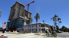 A cyclist rides by the construction site of a high-rise apartment building in Banker's Hill, July 25, 2025.