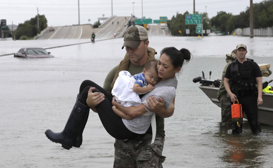 Houston Police SWAT officer Daryl Hudeck carries Catherine Pham and her 13-month-old son Aiden after rescuing them from their home surrounded by floodwaters from Tropical Storm Harvey in Houston on Sunday. The remnants of Hurricane Harvey sent devastating floods pouring into Houston Sunday as rising water chased thousands of people to rooftops or higher ground.