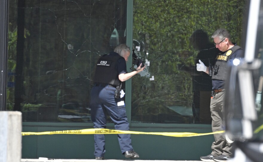 A Louisville Metro Police technician photographs bullet holes in the front glass of the Old National Bank building in Louisville, Ky., on Monday.
