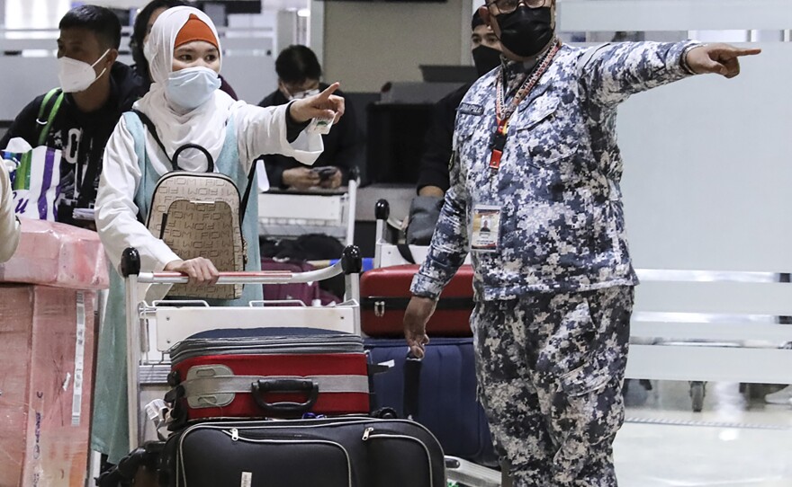 Members of the Philippine Coast Guard assist passengers as they arrive at Manila's International Airport, Philippines. The Philippines lifted a nearly 2-year ban on foreign travelers Thursday as an omicron-fueled surge eases.