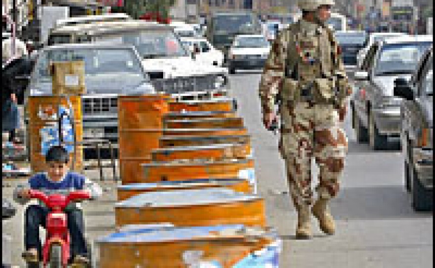 An Iraqi boy rides a tricycle as an Iraqi soldier patrols central Baghdad on Feb. 27, 2006. Authorities lifted a daytime curfew that had been imposed for three days.