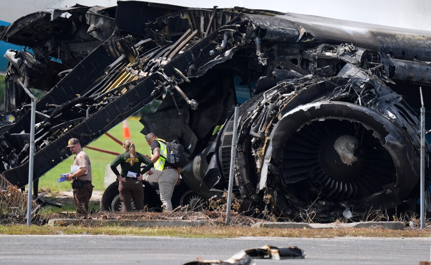 Officials stand near a destroyed wing and engine as they inspect an Amazon cargo plane two days after it overshot a runway at Miami International Airport, Tuesday, Sept. 8, 2026, in Miami.