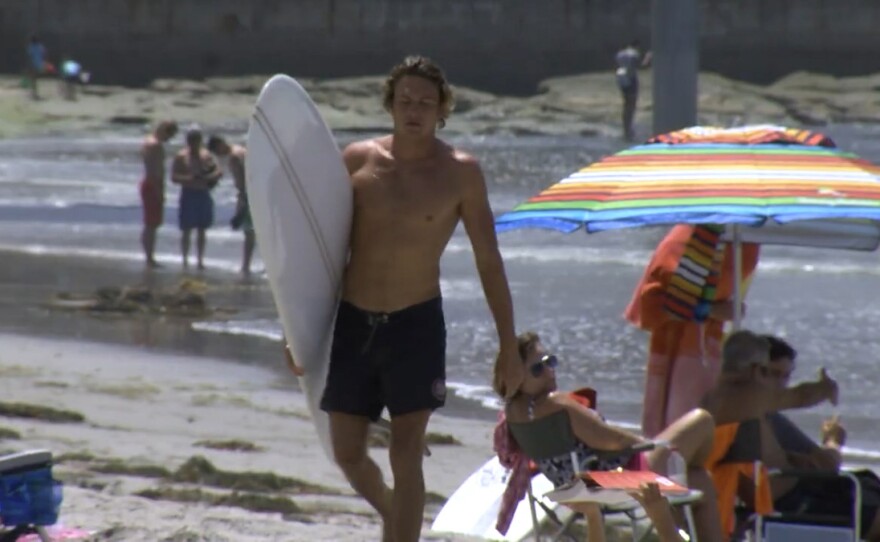 A surfer walking on a crowded beach in San Diego in this undated picture.