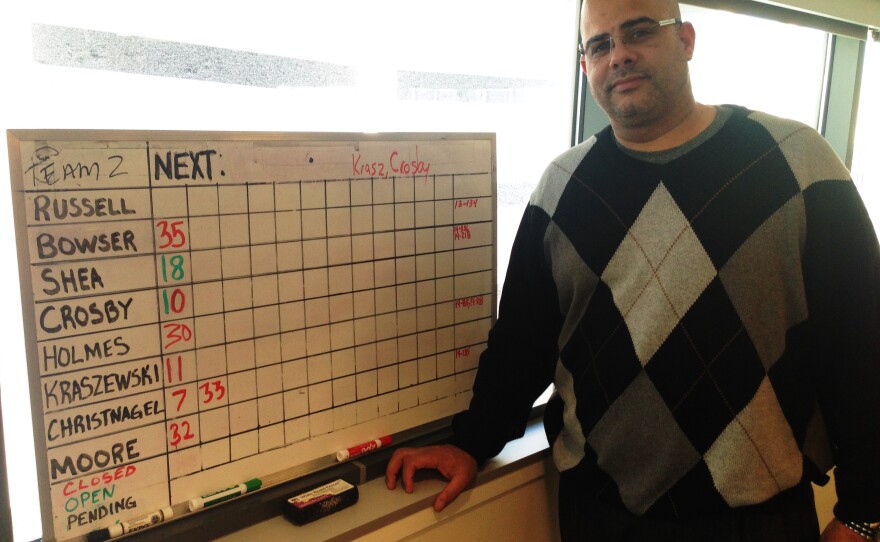 Detroit police officer James Kraszewski stands next to the white board the squad uses to track their cases' clearance status.
