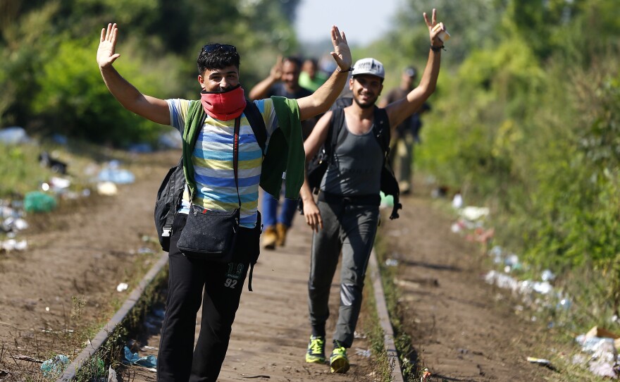 People celebrate as they arrive at the the border between Serbia and Hungary near Roszke, southern Hungary.