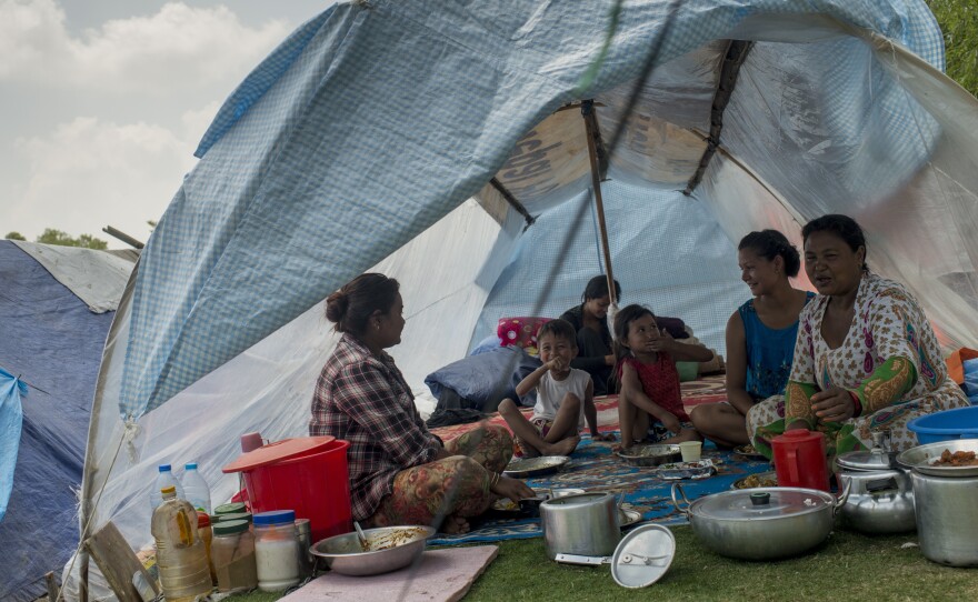 A family sits inside a tent at Kathmandu's golf course Wednesday, a day after a strong earthquake hit the area.