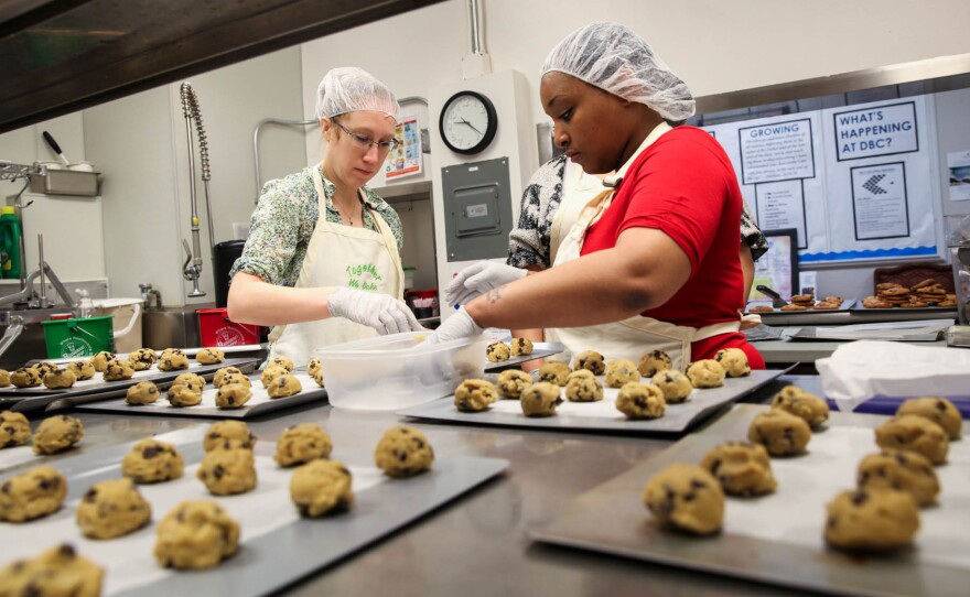 Elizabeth Bennett, director of partnerships, and Nikki Yates, program participant, place cookie dough they've just made onto baking sheets.