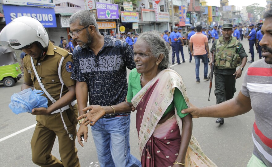 In Colombo, a woman is helped near St. Anthony's Shrine, the site of one of multiple explosions in Sri Lanka on Easter Sunday.