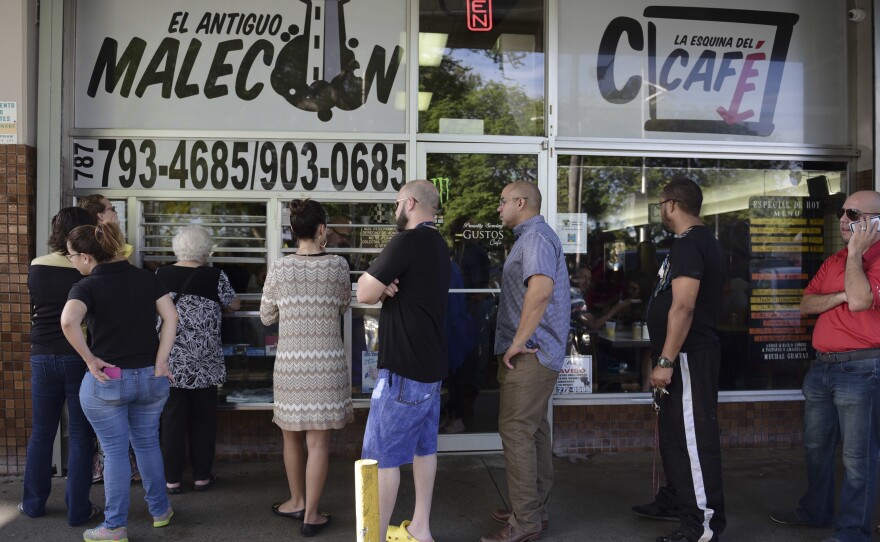 Customers stand in line at one of the few open cafeterias on Roosevelt Avenue, in San Juan, Puerto Rico, on Thursday.