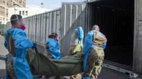 In this Jan. 12, 2021 photo provided by the Los Angeles County Department of Medical Examiner-Coroner, National Guard members assisting with processing COVID-19 deaths, placing them into temporary storage at the medical examiner-coroner's office in Los Angeles. 