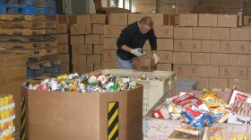 A volunteer does a rough sort of the donated food. He checks items and removes any that are dented or damaged. 