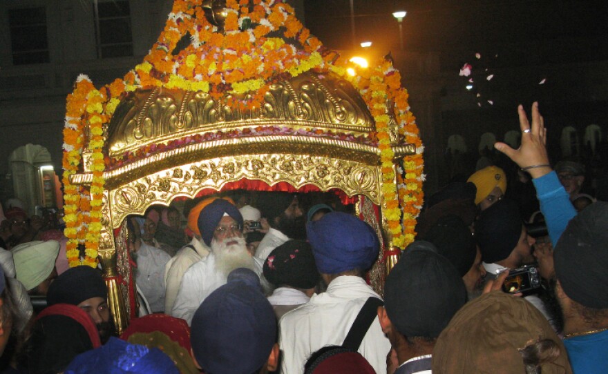 Devotees reach out to the gilded litter that carries the Sikh holy book, the Guru Granth Sahib, to the Golden Temple in Amritsar.