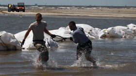 Louisiana National Guard members retrieve a sling load cable as helicopters drop sand bags into place as they create a barrier in an attempt to protect an estuary from the massive oil spill on May 10, 2010 in Lafourche Parish, Louisiana.