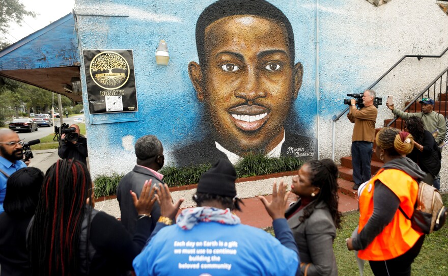 People gather in front of a mural of Ahmaud Arbery painted on the side of The Brunswick African American Cultural Center in Brunswick, Ga., on Thursday.