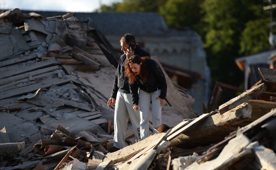 Residents stand among damaged buildings after a strong earthquake hit Amatrice on Wednesday. Central Italy was struck by a powerful, magnitude 6.2 earthquake in the early morning.