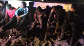 Some of the people detained by federal agents sit on the beach after coming ashore, August 24, 2017. 